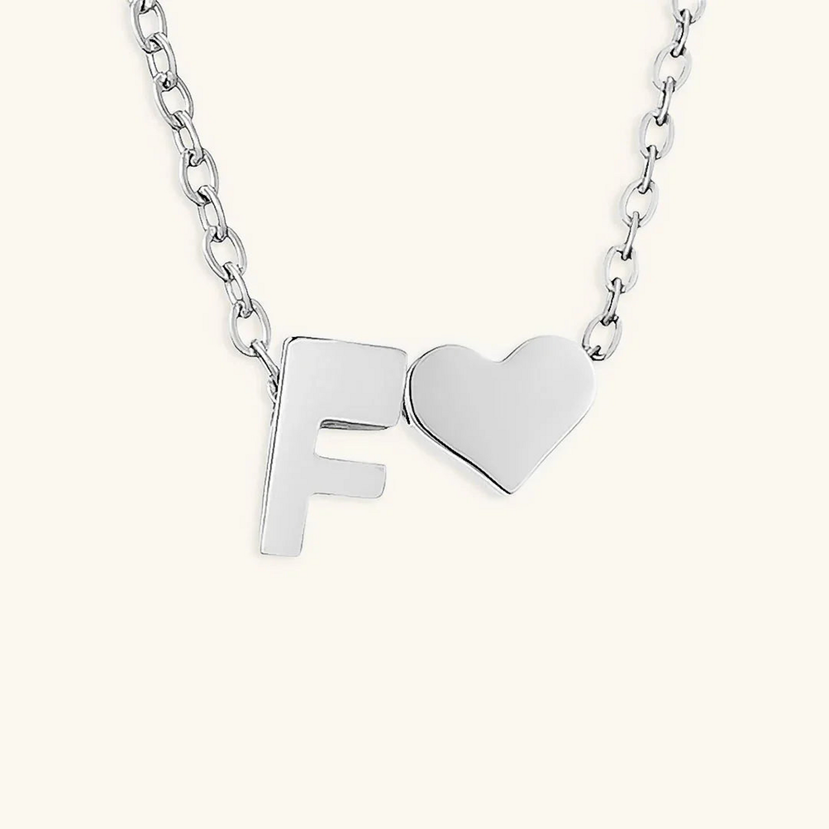 Seraya silver-tone initial F and heart necklace on an ivory background
