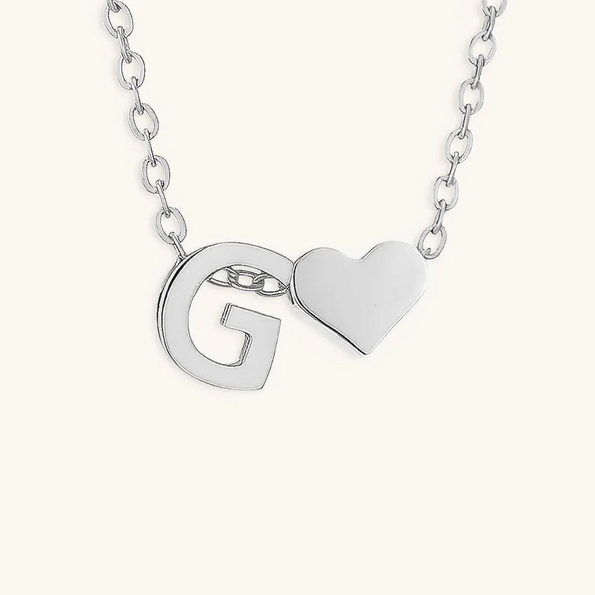 Seraya silver-tone initial G and heart necklace on an ivory background