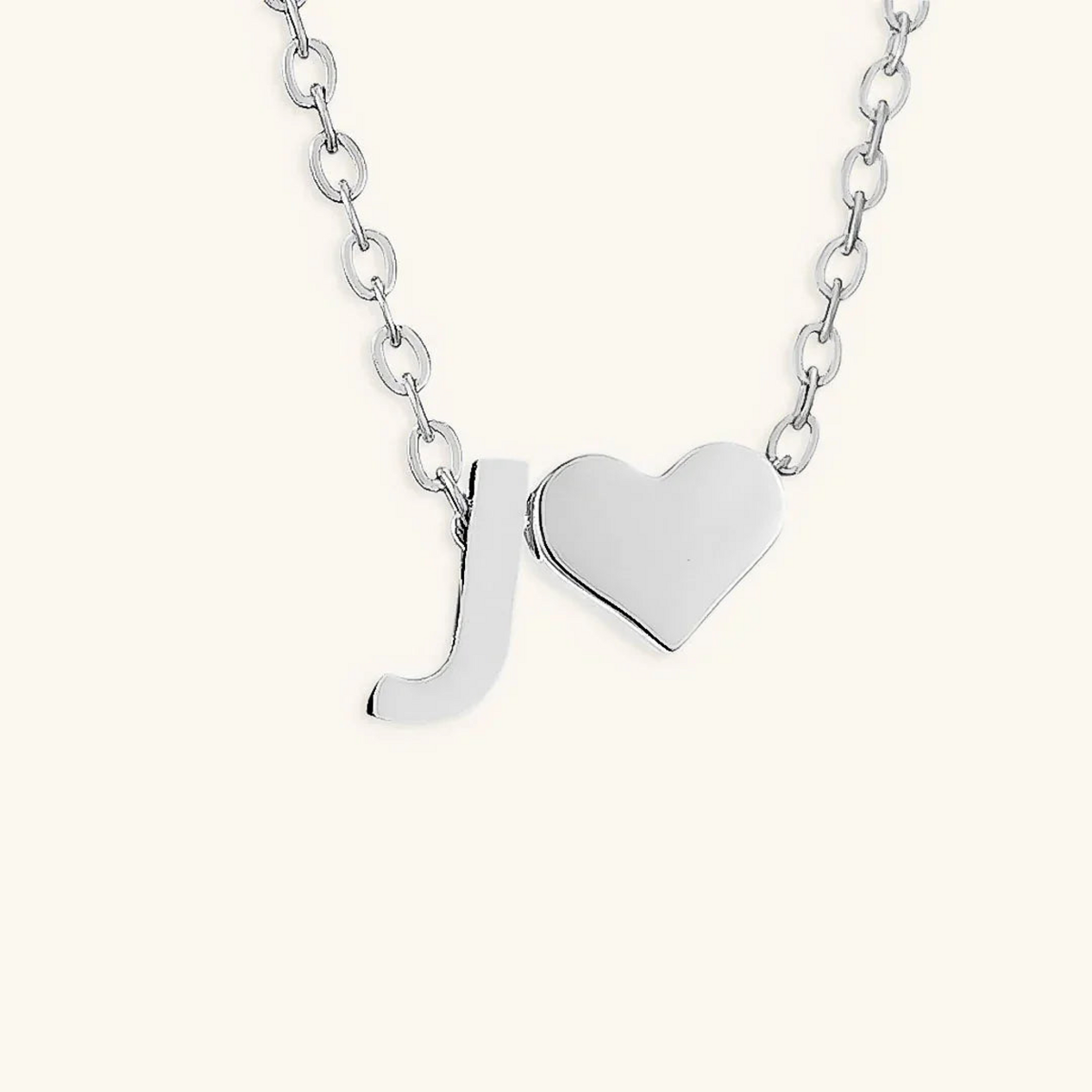 Seraya silver-tone initial J and heart necklace on an ivory background
